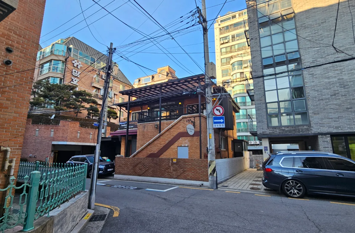 청담동 105-1 측면 – 경사진 골목을 따라 올라붙은 벽돌 외벽과 외부 계단