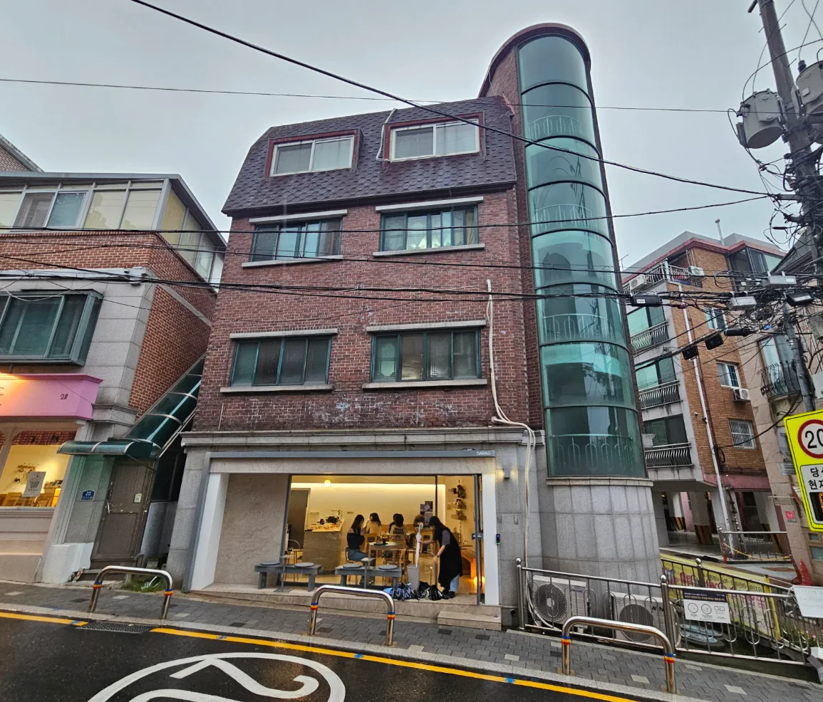 필운동 67 정면 – 통유리로 열린 1층 카페와 원통형 유리 계단실