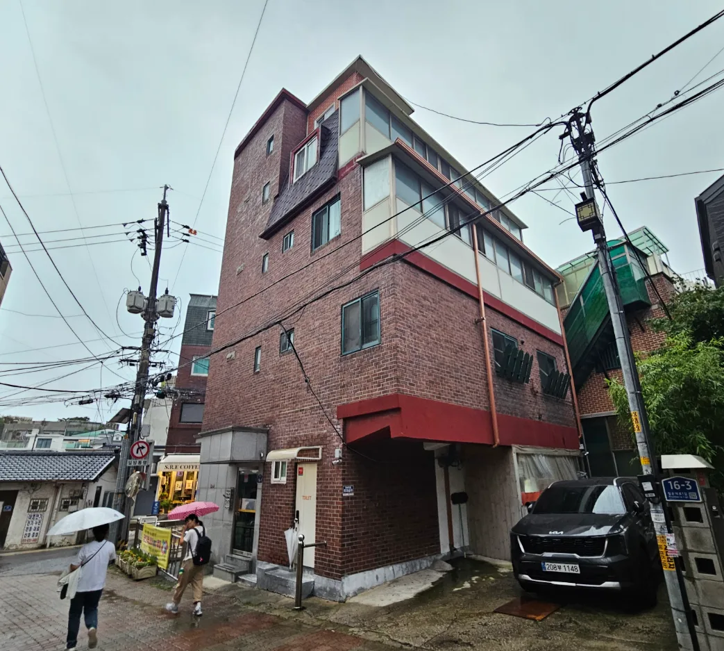 필운동 67 측면 – 두 방향 도로가 만나는 코너의 4층 벽돌 외관