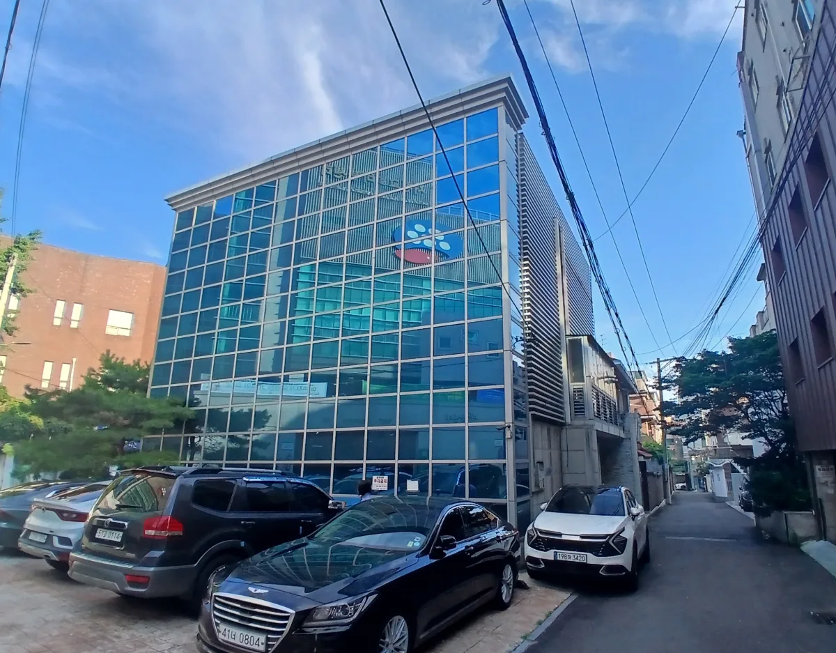 서교동 377-18 앞 골목 – 건물 옆 주차 공간과 맞붙은 유리 외관 이웃 건물